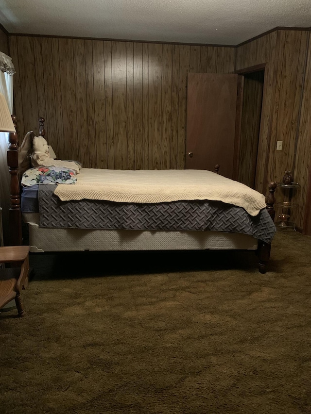 carpeted bedroom with a textured ceiling and wood walls