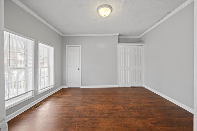 spare room featuring a textured ceiling, dark hardwood / wood-style floors, and ornamental molding