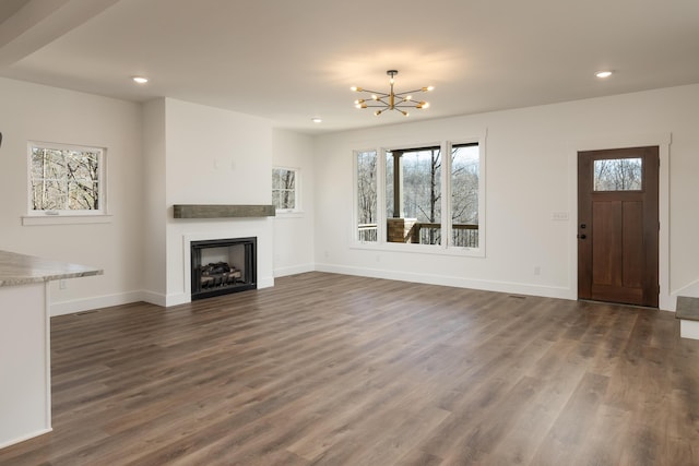 unfurnished living room with dark hardwood / wood-style floors and a chandelier