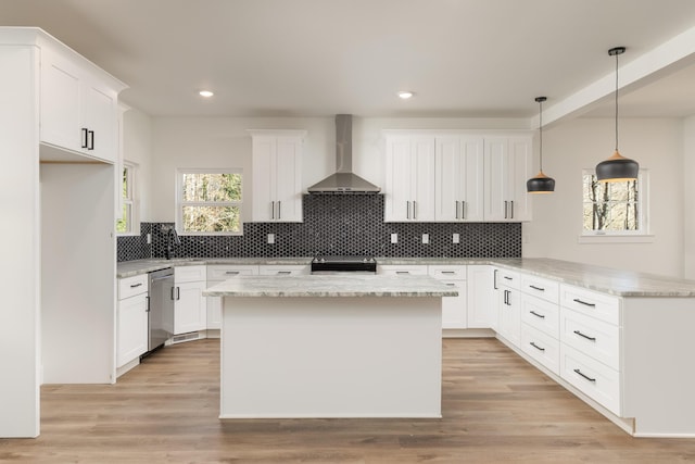 kitchen featuring wall chimney range hood, white cabinets, and stainless steel appliances