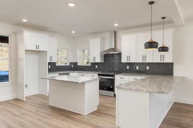 kitchen featuring pendant lighting, white cabinets, a center island, wall chimney exhaust hood, and electric range