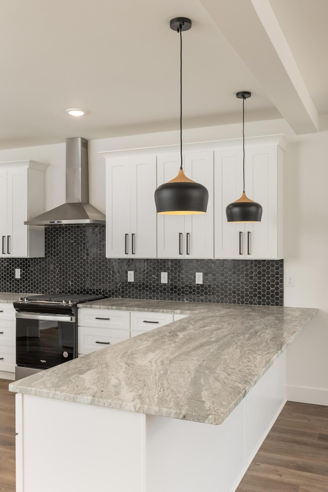 kitchen featuring white cabinetry, wall chimney range hood, and hanging light fixtures