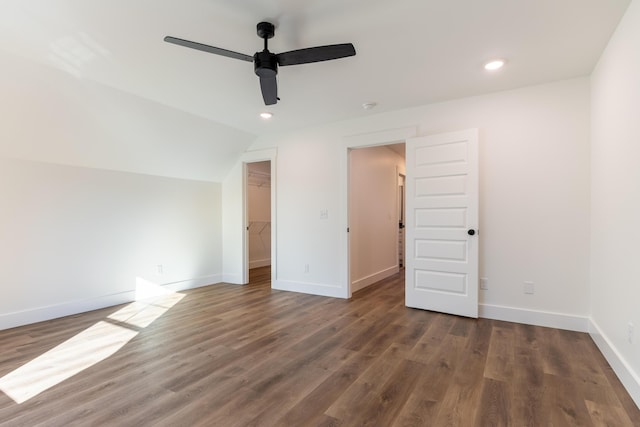 unfurnished bedroom with ceiling fan, lofted ceiling, a spacious closet, dark wood-type flooring, and a closet