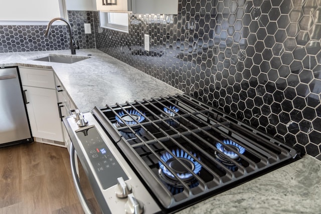 kitchen with white cabinetry, dark hardwood / wood-style flooring, stainless steel appliances, sink, and backsplash