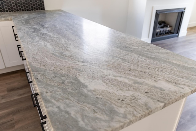 interior details featuring light stone countertops, white cabinets, and a center island