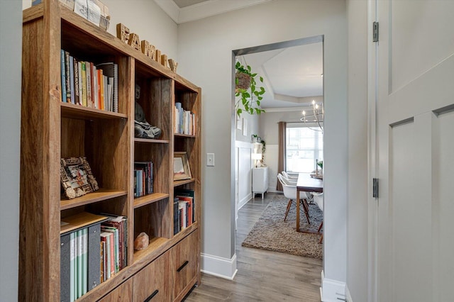 hall featuring an inviting chandelier, ornamental molding, and wood-type flooring