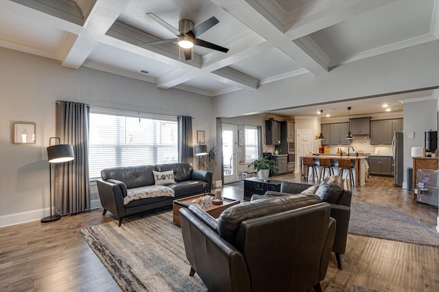 living room with sink, ornamental molding, and light wood-type flooring