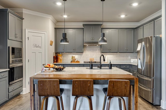 kitchen with sink, gray cabinets, stainless steel appliances, an island with sink, and decorative backsplash