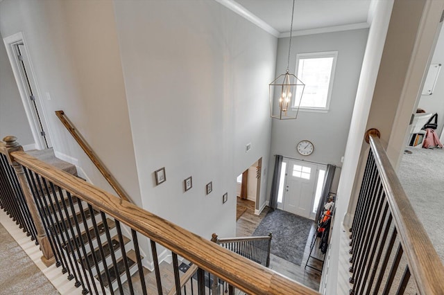 entrance foyer featuring crown molding, a towering ceiling, an inviting chandelier, and carpet flooring