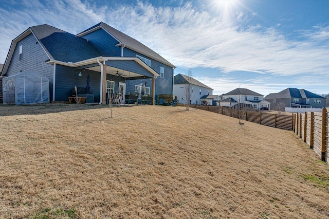 rear view of property featuring ceiling fan and a yard