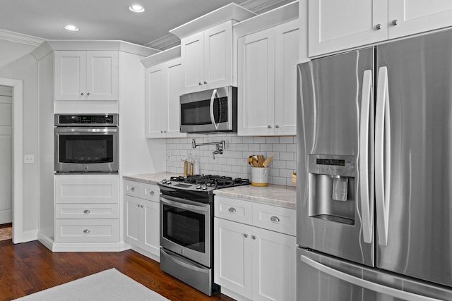 kitchen with white cabinets, appliances with stainless steel finishes, and light stone counters