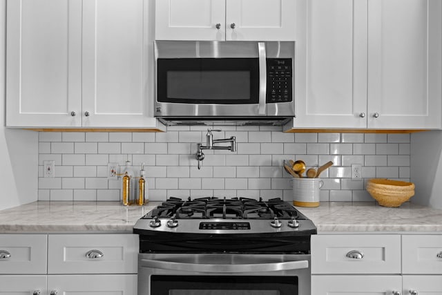 kitchen featuring white cabinetry, light stone countertops, backsplash, and appliances with stainless steel finishes