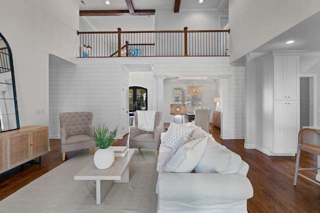 living room featuring beam ceiling, dark wood-type flooring, a high ceiling, and decorative columns