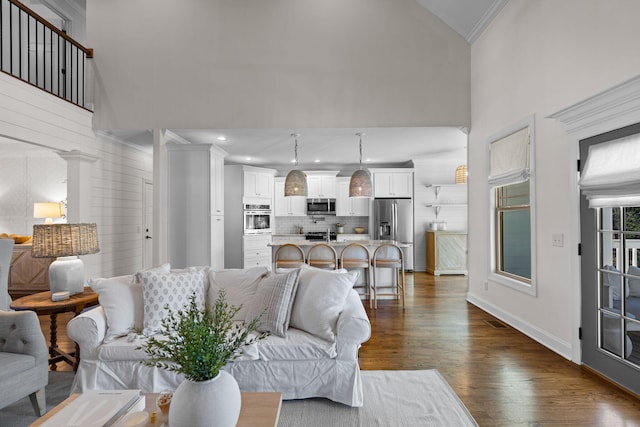 living room featuring dark hardwood / wood-style flooring, ornamental molding, and high vaulted ceiling