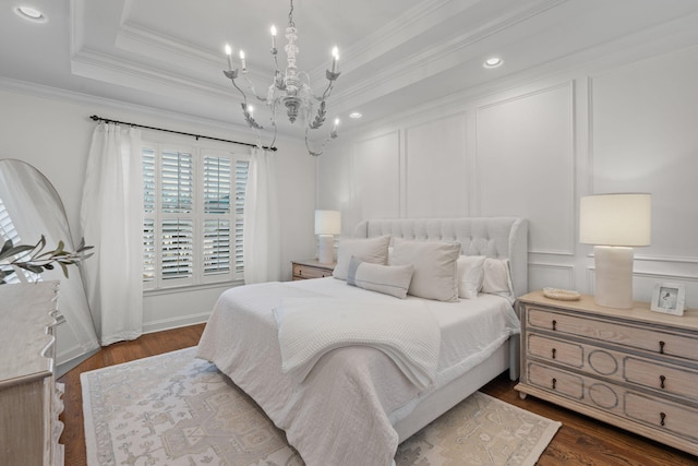 bedroom with a raised ceiling, dark hardwood / wood-style flooring, crown molding, and a chandelier