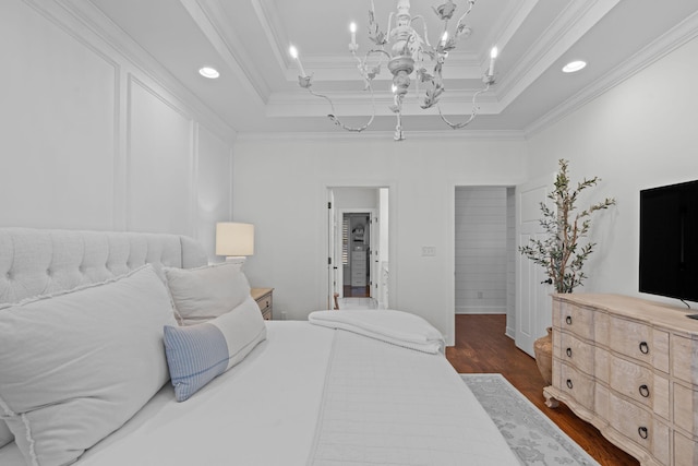 bedroom featuring crown molding, dark wood-type flooring, an inviting chandelier, and a tray ceiling