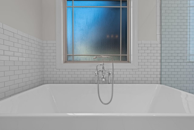 bathroom with a tub to relax in and tile walls