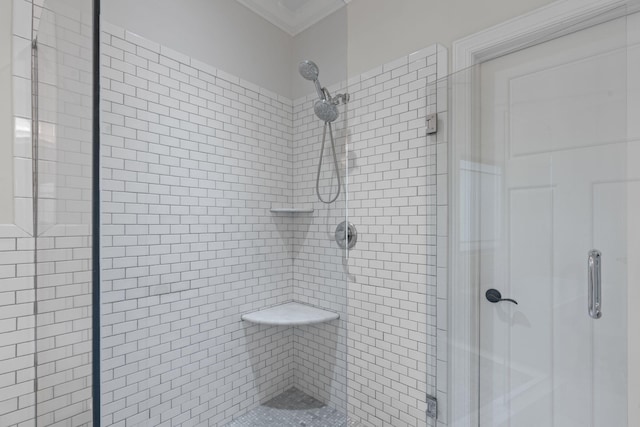 bathroom featuring a shower with shower door and crown molding