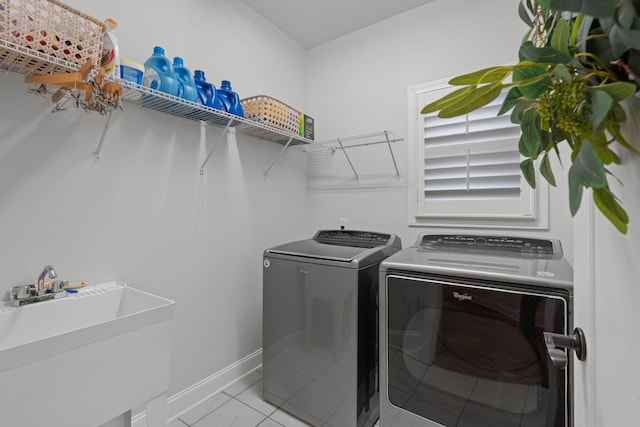 washroom with light tile patterned floors, washer and clothes dryer, and sink