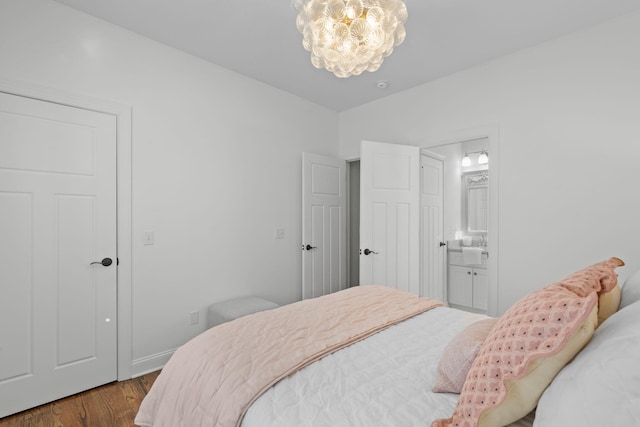 bedroom with an inviting chandelier, ensuite bathroom, and wood-type flooring