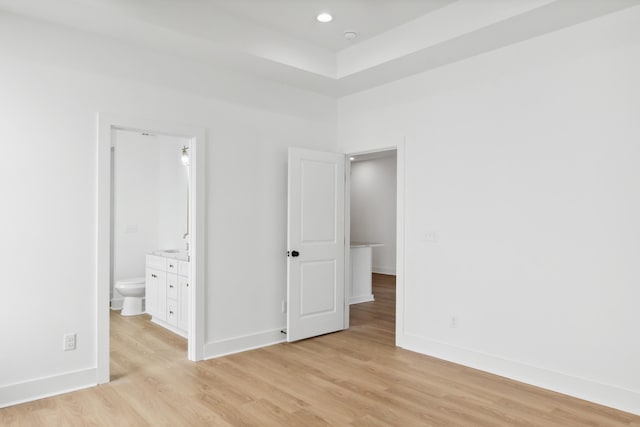 unfurnished bedroom featuring connected bathroom and light wood-type flooring