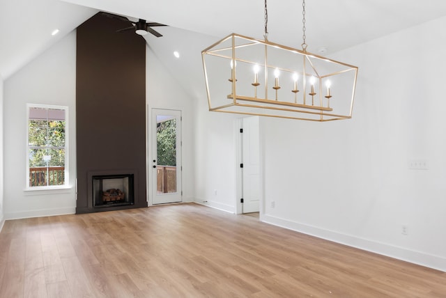 unfurnished living room with ceiling fan, light wood-type flooring, high vaulted ceiling, and a fireplace