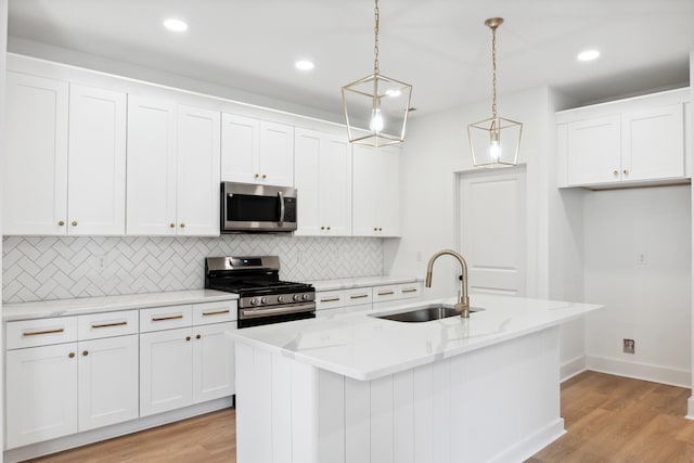 kitchen featuring sink, pendant lighting, stainless steel appliances, and an island with sink