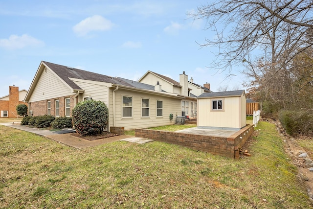 rear view of house featuring a patio area, an outbuilding, and a yard