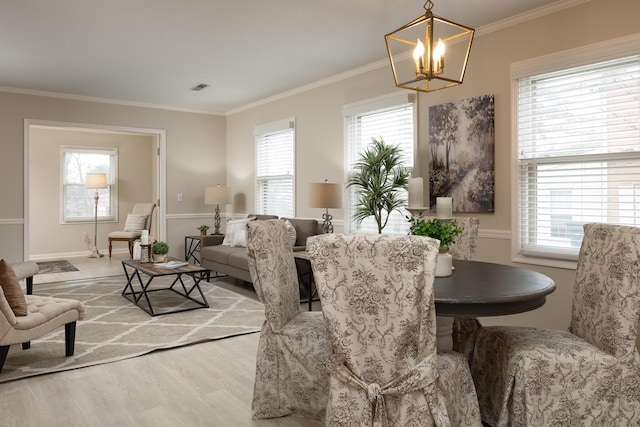 dining area with light hardwood / wood-style flooring, ornamental molding, and a chandelier