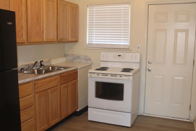 kitchen featuring sink, electric range, dark wood-type flooring, and black fridge