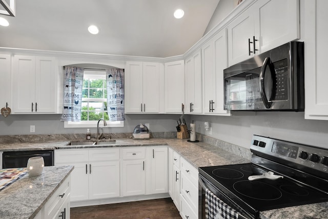 kitchen featuring light stone countertops, black appliances, lofted ceiling, white cabinetry, and sink