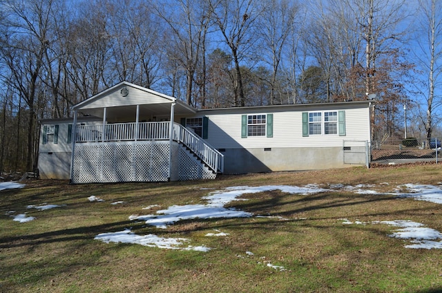 snow covered rear of property with covered porch and a yard