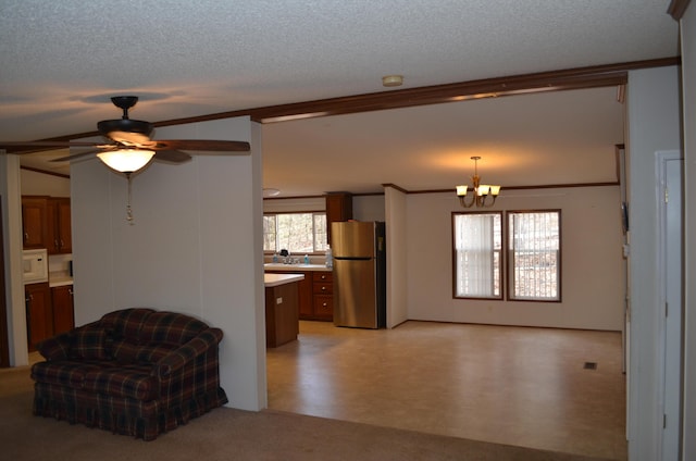 living room featuring a textured ceiling, ornamental molding, and ceiling fan with notable chandelier