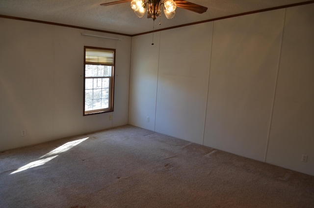 carpeted spare room featuring a textured ceiling, ceiling fan, and ornamental molding