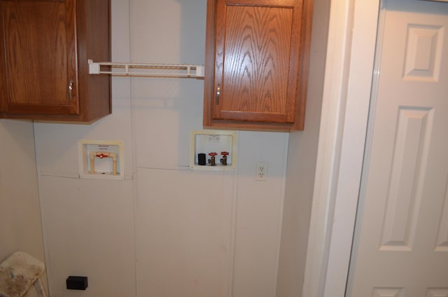 clothes washing area featuring hookup for a washing machine and cabinets