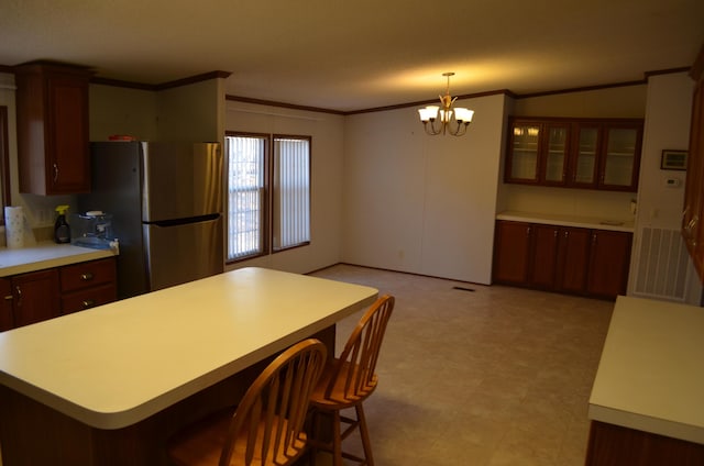 kitchen with decorative light fixtures, stainless steel fridge, a notable chandelier, a breakfast bar, and crown molding