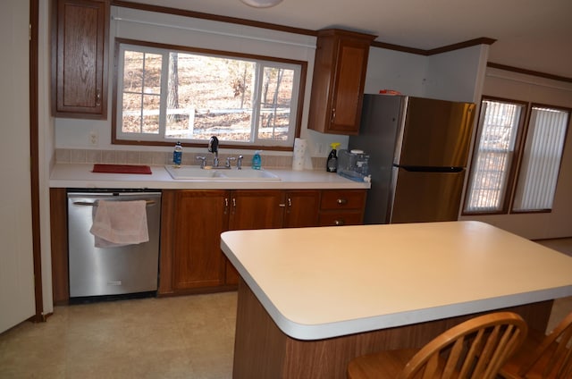 kitchen with sink, a kitchen breakfast bar, appliances with stainless steel finishes, and ornamental molding