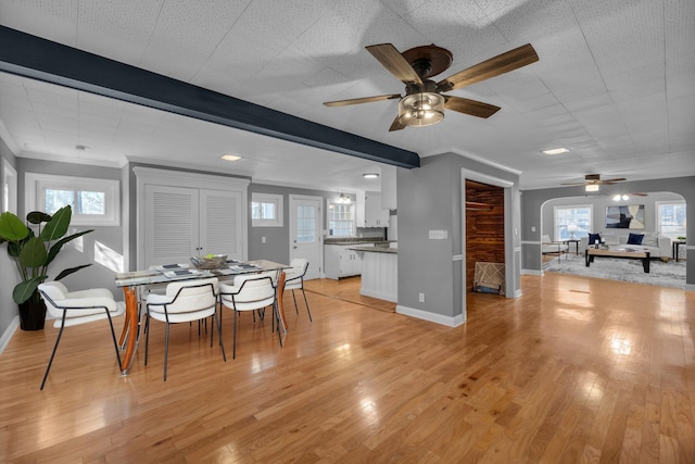 dining room featuring light hardwood / wood-style flooring, crown molding, beamed ceiling, and a healthy amount of sunlight