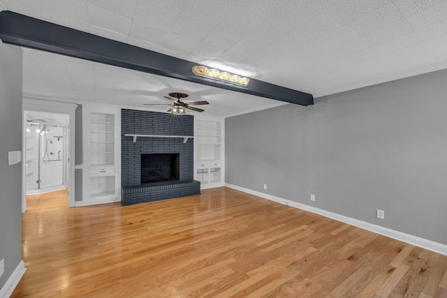 unfurnished living room with beamed ceiling, light hardwood / wood-style floors, a brick fireplace, built in features, and ceiling fan