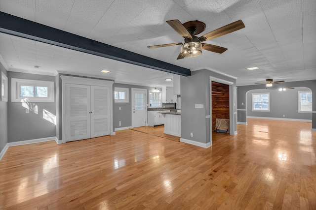 unfurnished living room with ceiling fan, ornamental molding, light hardwood / wood-style floors, and plenty of natural light