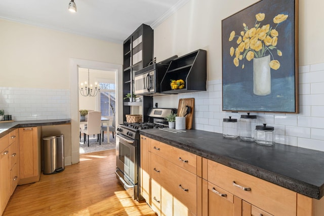 kitchen with crown molding, light hardwood / wood-style flooring, a notable chandelier, stainless steel gas range oven, and decorative backsplash