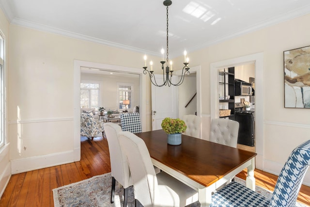 dining space featuring hardwood / wood-style flooring, ornamental molding, and a notable chandelier