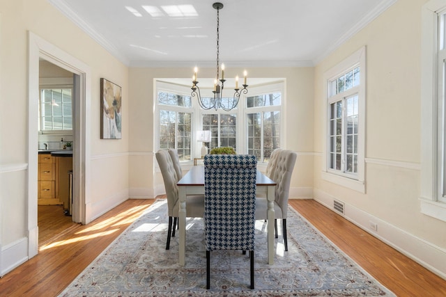 dining area featuring hardwood / wood-style floors, ornamental molding, and a healthy amount of sunlight