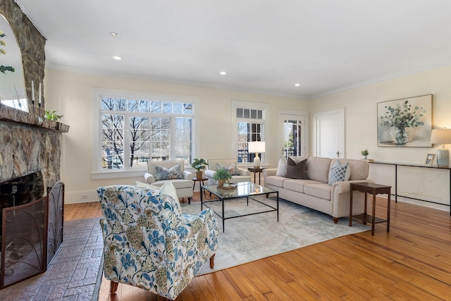 living room with light wood-type flooring, crown molding, a fireplace, and plenty of natural light