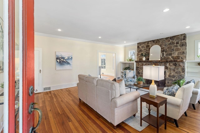 living room featuring a fireplace, wood-type flooring, and ornamental molding