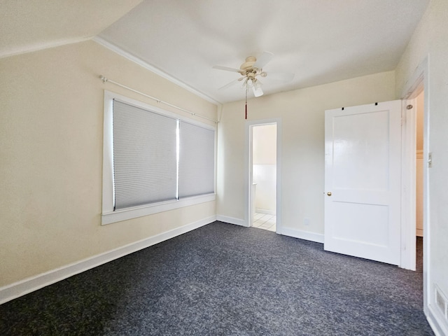 unfurnished bedroom featuring vaulted ceiling, ensuite bathroom, ceiling fan, and dark colored carpet