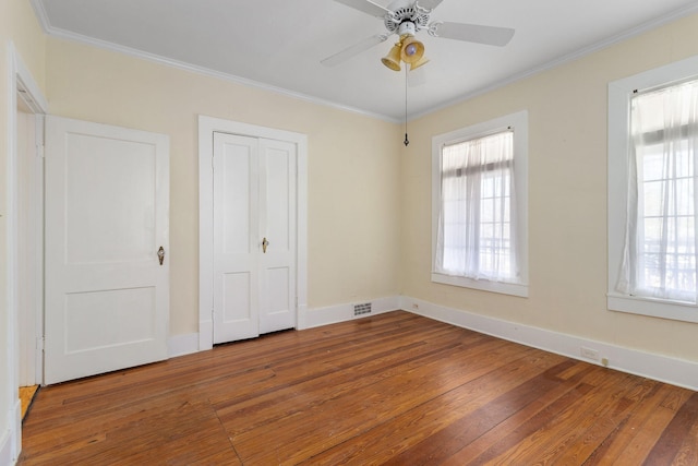 unfurnished bedroom with ornamental molding, hardwood / wood-style floors, and multiple windows