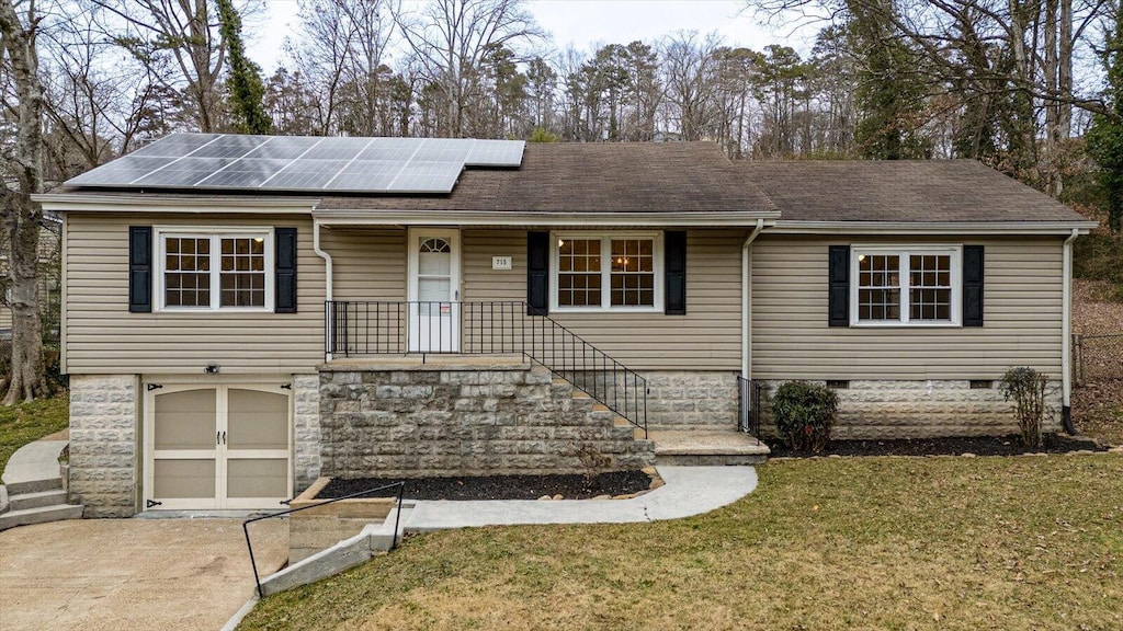 ranch-style home featuring a front yard, a garage, and solar panels