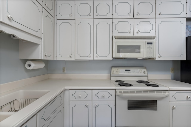 kitchen featuring sink, white appliances, and white cabinetry