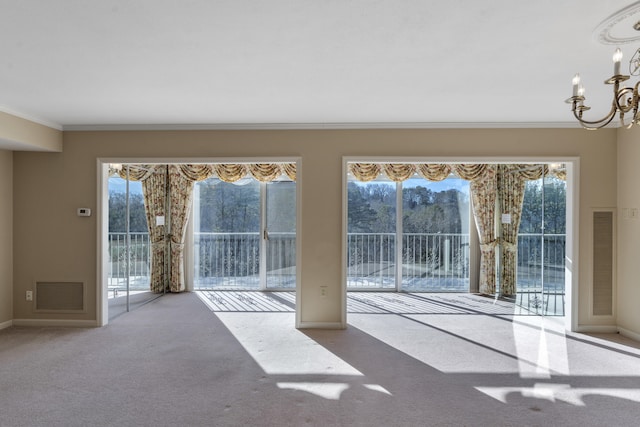 doorway featuring light carpet, a wealth of natural light, a notable chandelier, and ornamental molding